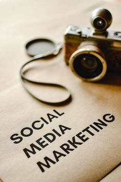 a camera sitting on top of a paper with the words social media marketing written on it