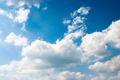 the sky is filled with white clouds and some green grass in front of an open field