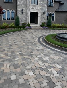 a brick driveway in front of a large house