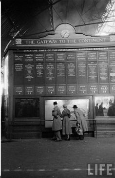 two people standing in front of a train station with information about the subway system on it