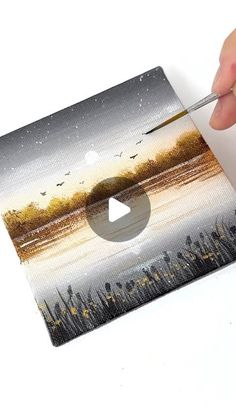 someone is painting a landscape with acrylic paint on the paper and using scissors