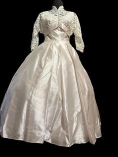 a white wedding dress on display against a black background