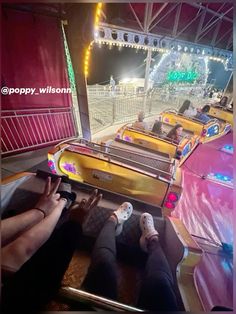 people are sitting on roller coasters in an amusement park at night with colorful lights