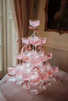 a table topped with lots of wine glasses on top of a round table covered in pink ribbon