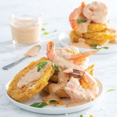 two white plates topped with fried shrimp and grits next to a jar of sauce