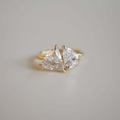 three pear shaped diamond engagement rings in yellow gold, set against a plain white background