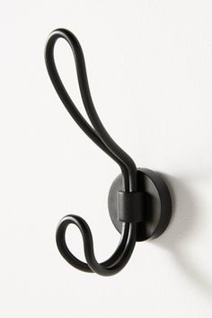 a black hook is attached to the side of a white wall with a curved handle