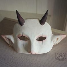 a white mask with horns on it sitting on a table