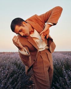 a man standing in front of a lavender field with his hands on his chest and looking down