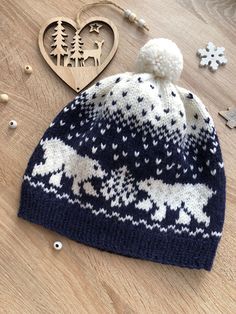 a blue and white knitted hat sitting on top of a wooden table next to a heart shaped ornament