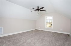 an empty room with a ceiling fan and carpeted floor in front of a window