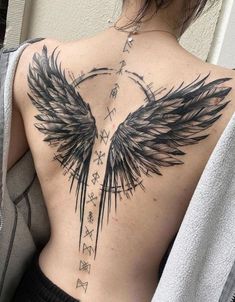 a woman's back with black wings and arrows on her upper half - back