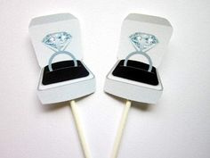 two wedding cake pops decorated with an engagement ring and diamond in the middle, on top of each other