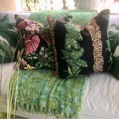 three pillows on a couch covered in green and pink floral fabric with leopard print trim