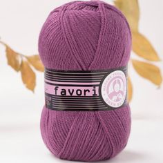 a purple ball of yarn sitting on top of a white table next to a plant