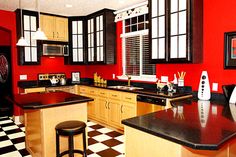 a kitchen with black and white checkered flooring, red walls and wooden cabinets