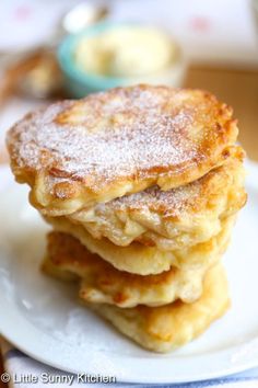 three pancakes stacked on top of each other on a white plate with powdered sugar