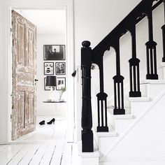 an open door leading to a white room with black railings and pictures on the wall