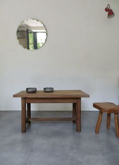 a table and two stools in front of a wall with a mirror on it