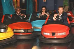 three people are riding bumper cars in an indoor ride - on area at the amusement park