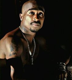 a man with tattoos on his chest wearing a chain around his neck and holding a cell phone