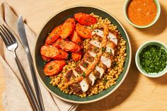 a plate with chicken, carrots and corn next to two bowls of seasoning