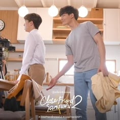 two young men standing in a kitchen next to each other holding bags and looking at the camera