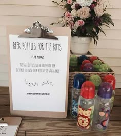 a sign that says beer bottles for the boys on it next to some fruit and flowers