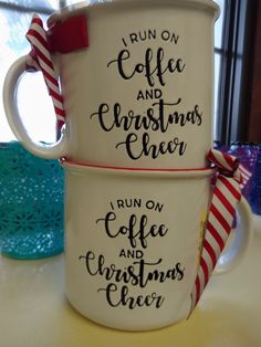 two coffee mugs sitting on top of a table next to each other with christmas decorations