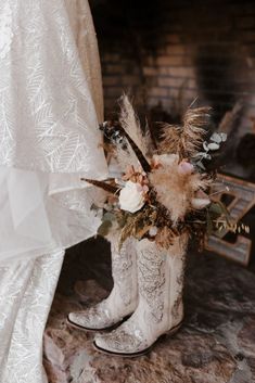 a close up of a boot with flowers and feathers on the ground next to a fireplace