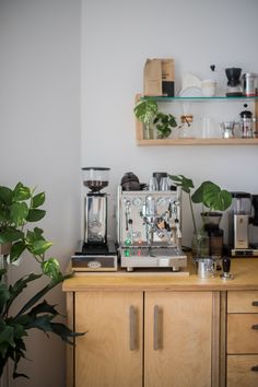 a coffee maker sitting on top of a wooden counter next to a potted plant