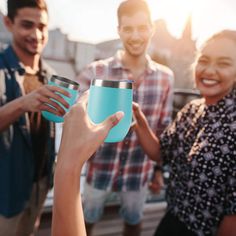 three people are holding up cups in front of each other and smiling at the camera