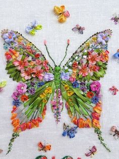 a butterfly made out of flowers on a white cloth with butterflies flying around the image