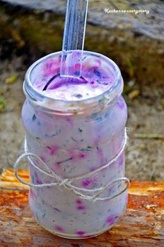 a jar filled with liquid sitting on top of a piece of wood next to a tree