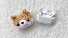 an apple airpods case sitting on top of a white fur covered floor next to an earbud