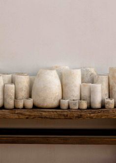 several white vases sitting on top of a wooden shelf