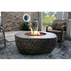 a fire pit sitting on top of a stone floor next to a chair and table