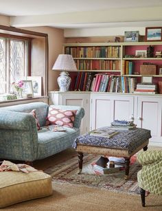 a living room filled with lots of furniture and bookshelves next to a window