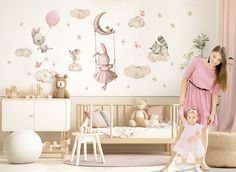 a woman standing next to a baby in a room with wall decals on the walls