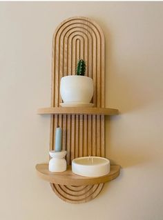 a wooden shelf with two bowls and a plant on it