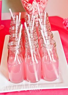 there are many pink drinks in mason jars on the table with candy sticks sticking out of them