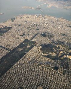 an aerial view of a large city with lots of buildings and water in the background