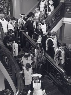 an old black and white photo of people on the stairs in a building with boxes