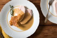 two white plates topped with food on top of a wooden table next to each other