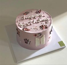 a pink birthday cake sitting on top of a table