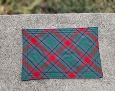 a green and red checkered cloth sitting on top of a cement wall