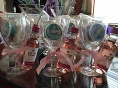 several wine glasses and bottles are sitting on a table with pink ribbon around the edges