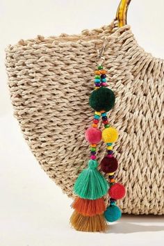 a straw bag with tassels and pom - poms hanging from it