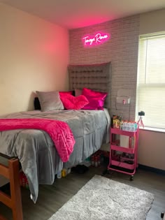 a bed room with a neatly made bed and a pink neon sign on the wall