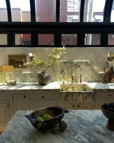 a kitchen with marble counter tops and an abundance of vases in the window sill